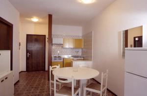 uma cozinha com uma mesa branca e cadeiras em RESIDENCE GARDEN -WALTERIGATO Apartments SOLO PER FAMIGLIE em Lido di Jesolo