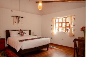 a bedroom with a bed and a window at La Rosa Wellness Lodge in Urubamba