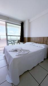 un lit blanc dans une chambre avec une grande fenêtre dans l'établissement West Flat Studio30 na Nova Betânia - INNOVA, à Mossoró