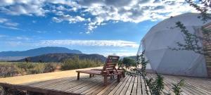 a wooden deck with a chair and a tent at Domos del Viento in Cafayate