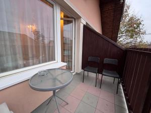 a glass table and two chairs on a balcony at AIRPORTMAX Panzió in Vecsés