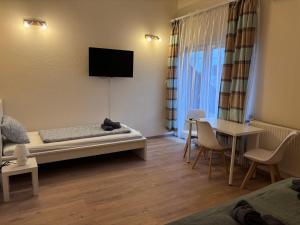 a room with a bed and a table and a television at AIRPORTMAX Panzió in Vecsés
