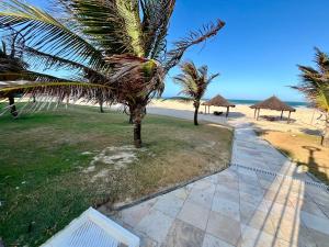 a pathway leading to a beach with palm trees and umbrellas at Terramaris - Paraíso Pé na areia in Aquiraz