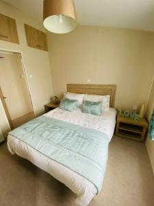 a bedroom with a large bed with blue pillows at DELUXE MEADOWS NOOK LODGE - Cornwall Hideaway Lodge in Newquay +5 photos