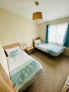 a bedroom with two beds and a window at DELUXE MEADOWS NOOK LODGE - Cornwall Hideaway Lodge in Newquay