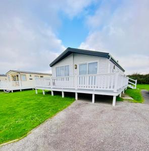 a large white mobile home with a porch at DELUXE MEADOWS NOOK LODGE - Cornwall Hideaway Lodge in Newquay