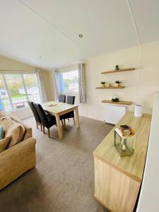 a living room with a table and a couch at DELUXE MEADOWS NOOK LODGE - Cornwall Hideaway Lodge in Newquay