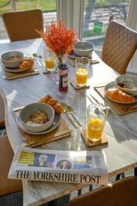 a table with food and orange juice and a newspaper at Large 2-3 Bed FREE Parking, En-suite in Harrogate