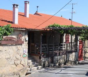 a stone building with a red roof and a balcony at Casa-Museo Genia Trigo in Sober