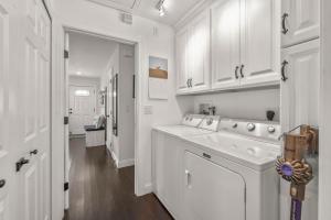 a kitchen with white cabinets and a washer and dryer at Weeden Cottage in Saint Augustine
