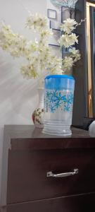 Un jarrón encima de una cómoda con un florero. en Shriji Home stay, en Mathura