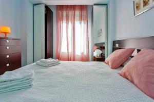 ein Schlafzimmer mit einem großen weißen Bett mit rosa Kissen in der Unterkunft La Torre de la Catedral - Ole Solutions in Jerez de la Frontera