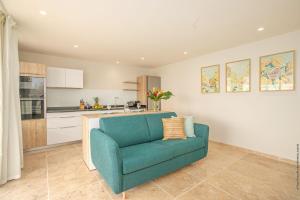 a living room with a blue couch and a kitchen at Villas Tangarane in Les Trois-Îlets +30 photos