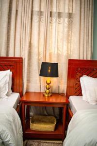 ein Schlafzimmer mit zwei Betten und einem Tisch mit Lampe in der Unterkunft ILBORU HAVEN HOMEs in Arusha + 3 Fotos