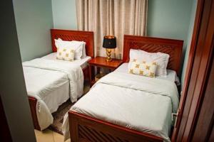 ein Schlafzimmer mit zwei Betten und einem Tisch mit Lampe in der Unterkunft ILBORU HAVEN HOMEs in Arusha