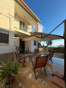 eine Terrasse mit Tisch, Stühlen und Sonnenschirm in der Unterkunft Solemar2 in Giardina Gallotti