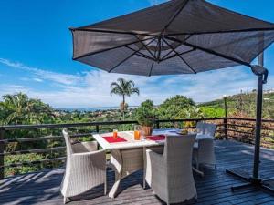 a table and chairs on a deck with an umbrella at Ekuthuleni Modern Christian Guesthouse with seaview in Umhlanga Ridge