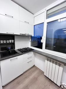 a white kitchen with a stove and a window at Nubia Modern Apartment in Craiova