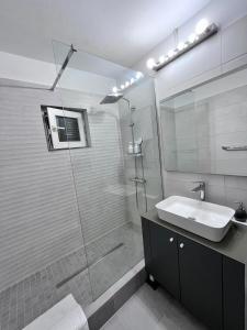 a bathroom with a glass shower and a sink at Nubia Modern Apartment in Craiova