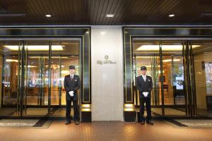 dos hombres con trajes parados frente a un edificio en Hotel New Otani Hakata, en Fukuoka