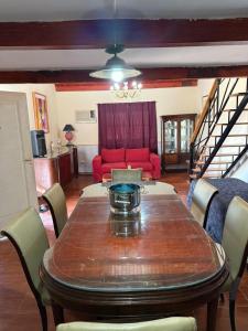 a dining room with a table and a red couch at Casa feliza in Villa Dolores