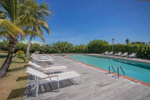 a row of white lounge chairs next to a swimming pool at Le Spot - Unique house with view in Oyster Pond