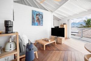 a living room with a television and a table at Le Spot - Unique house with view in Oyster Pond