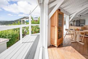 a white porch with a table on a wooden deck at Le Spot - Unique house with view in Oyster Pond
