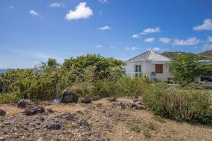 a white house sitting on top of a hill at Le Spot - Unique house with view in Oyster Pond