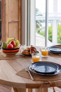 a table with plates of food and a bowl of fruit at Le Spot - Unique house with view in Oyster Pond