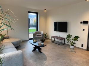 a living room with a couch and a table and a tv at Maison Impression vakantiehuis in Middelkerke