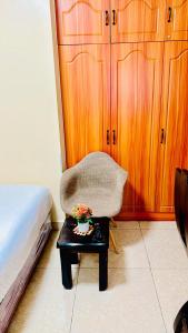 a bedroom with a chair and a table with flowers on it at Rosette Haven 2 in Nairobi