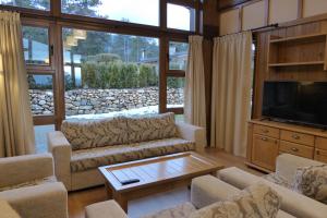 a living room with couches and a flat screen tv at Pirin Nest Villa in Bansko