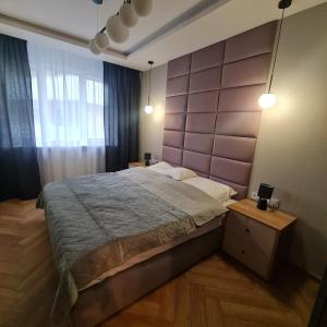 a bedroom with a large bed with a purple headboard at Central Park Green Apartament in Wrocław