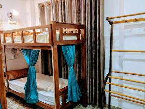 a couple of bunk beds with blue curtains in a room at Costels Mirissa in Mirissa