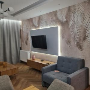 a living room with a couch and a tv on a wall at Central Park Green Apartament in Wrocław
