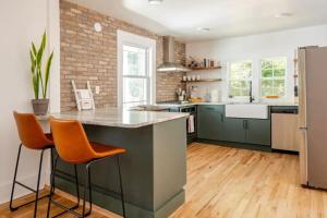 a kitchen with green cabinets and orange bar stools at Downtown Greenway Getaway in Raleigh