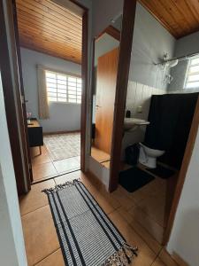 een badkamer met een toilet, een spiegel en een tapijt bij Chale Floresta in Campos do Jordão