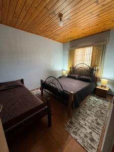 een slaapkamer met twee bedden en een houten plafond bij Chale Floresta in Campos do Jordão