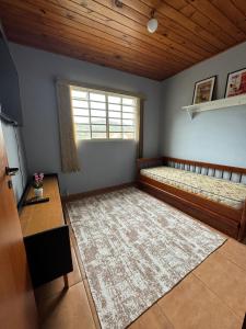 een slaapkamer met een bed, een raam en een tapijt bij Chale Floresta in Campos do Jordão
