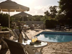 a table with drinks and an umbrella next to a pool at AQUARIUS HOTEL in Vasilikos