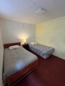 a bedroom with two beds and a lamp in it at Hotel Nativo in Santiago