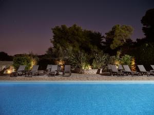 a group of chairs and a swimming pool at night at AQUARIUS HOTEL in Vasilikos