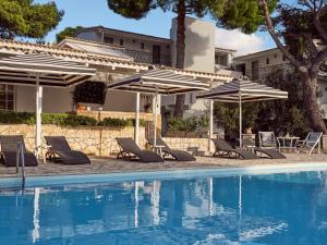 a group of chairs and umbrellas next to a pool at AQUARIUS HOTEL in Vasilikos