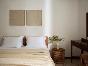 a bedroom with a bed with white sheets and a table at AQUARIUS HOTEL in Vasilikos