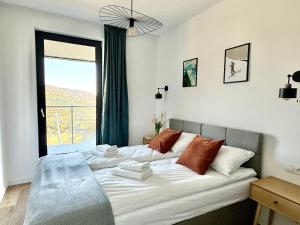 twee bedden in een kamer met een groot raam bij OWysoko - Apartamenty z Widokiem 200 m od tras Szczyrk Mountain Resort in Szczyrk