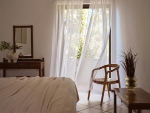 a bedroom with a bed and a chair and a window at AQUARIUS HOTEL in Vasilikos