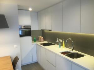 a kitchen with white cabinets and a sink at Studio Appartement Van Bunnenplein in Knokke-Heist