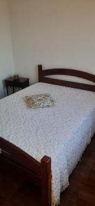 a bed with a white blanket on top of it at Paraíso da Tia Ana in Saquarema