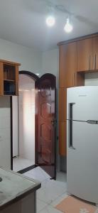 a kitchen with a white refrigerator and wooden cabinets at Paraíso da Tia Ana in Saquarema